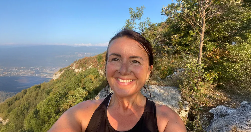 Paola, aide à domicile en Haute-Savoie, souriante devant le paysage du Val des Usses